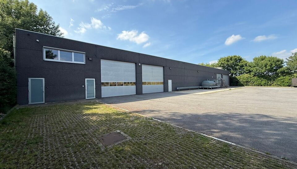 Ruime bedrijfssite met nieuwbouw kantoorgebouw, achterliggende loods van circa 1.680 m&sup2; en aansluitend weiland.
Vooraan aan de straat bevindt zich een recent en luxueus kantoorgebouw met ca. 160 m&sup2; bebouwde oppervlakte, bestaande uit gelijkvloers, eerst