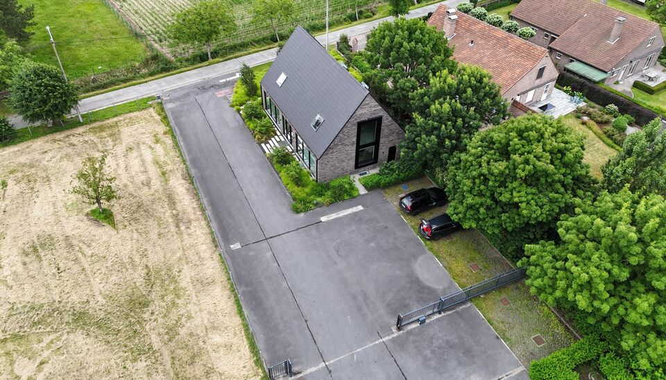 Ruime bedrijfssite met nieuwbouw kantoorgebouw, achterliggende loods van circa 1.680 m&sup2; en aansluitend weiland.
Vooraan aan de straat bevindt zich een recent en luxueus kantoorgebouw met ca. 160 m&sup2; bebouwde oppervlakte, bestaande uit gelijkvloers, eerst