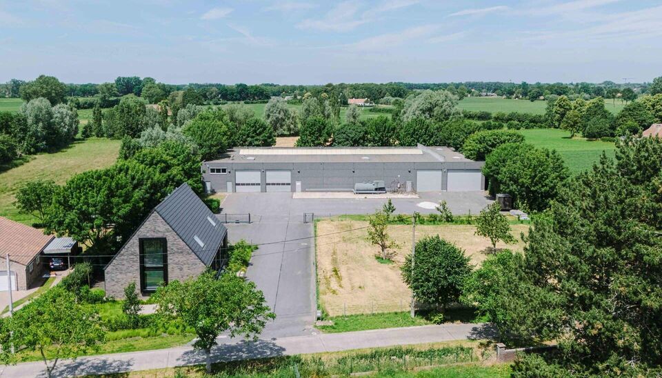 Ruime bedrijfssite met nieuwbouw kantoorgebouw, achterliggende loods van circa 1.680 m&sup2; en aansluitend weiland.
Vooraan aan de straat bevindt zich een recent en luxueus kantoorgebouw met ca. 160 m&sup2; bebouwde oppervlakte, bestaande uit gelijkvloers, eerst
