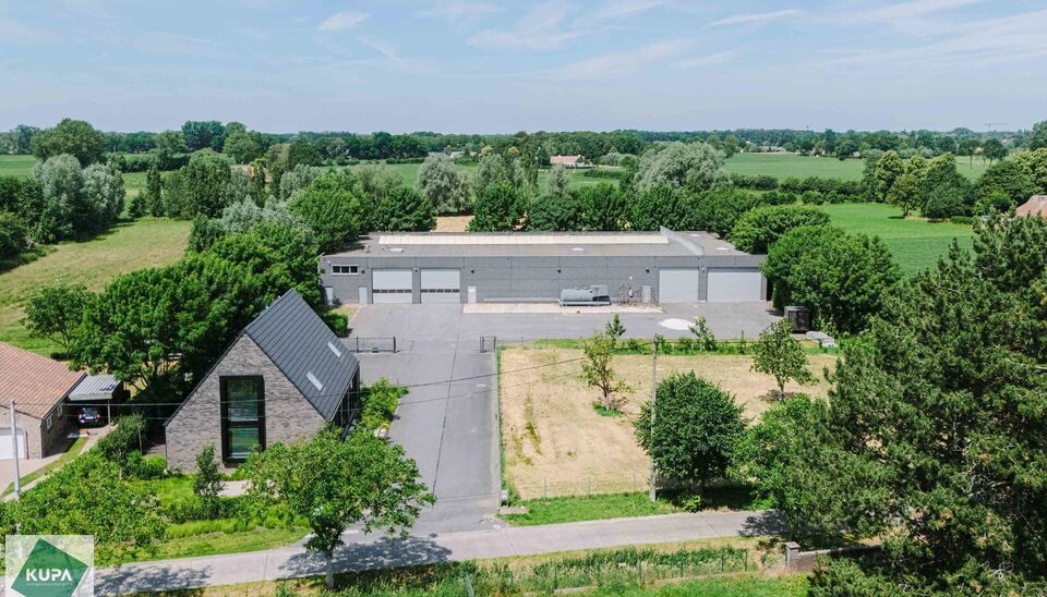 Ruime bedrijfssite met nieuwbouw kantoorgebouw, achterliggende loods van circa 1.680 m&sup2; en aansluitend weiland.
Vooraan aan de straat bevindt zich een recent en luxueus kantoorgebouw met ca. 160 m&sup2; bebouwde oppervlakte, bestaande uit gelijkvloers, eerst