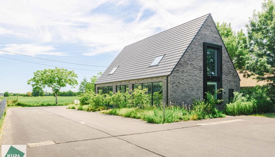 Ruime bedrijfssite met nieuwbouw kantoorgebouw, achterliggende loods van circa 1.680 m&sup2; en aansluitend weiland.
Vooraan aan de straat bevindt zich een recent en luxueus kantoorgebouw met ca. 160 m&sup2; bebouwde oppervlakte, bestaande uit gelijkvloers, eerst